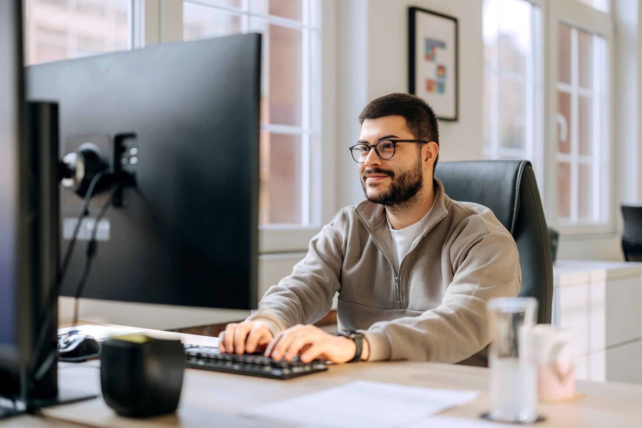 Professional web designer working at a desktop computer in a modern office