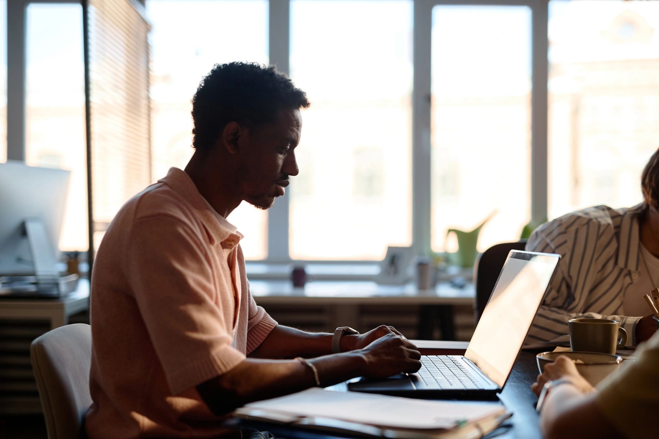 Team member working on a laptop during a collaborative office meeting